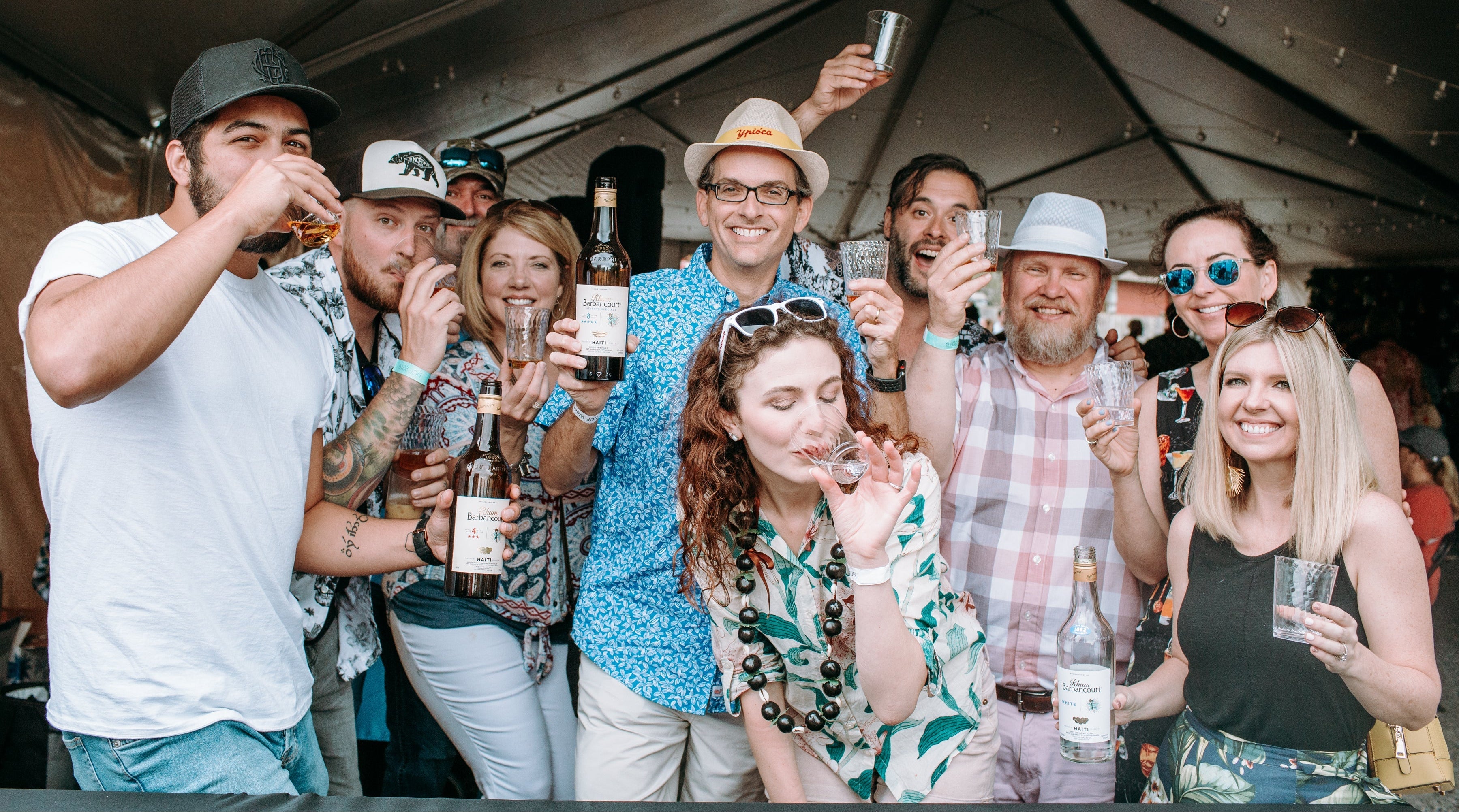 Group of people at the cocktail festival and raising glasses together.